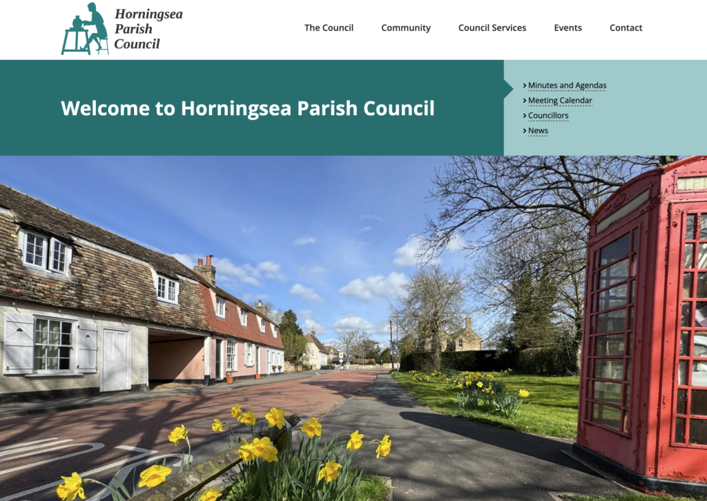 An image of a website showing a village high street with a traditional red phone box and daffodils.