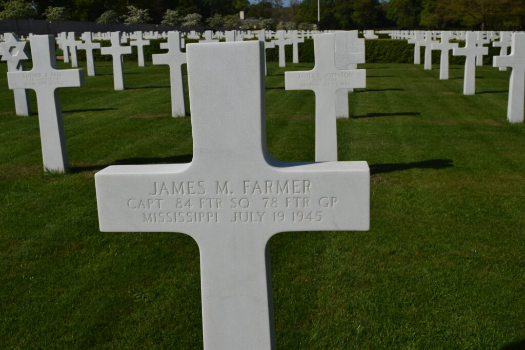 A white cross surrounded by many other white crosses on a green grassy field