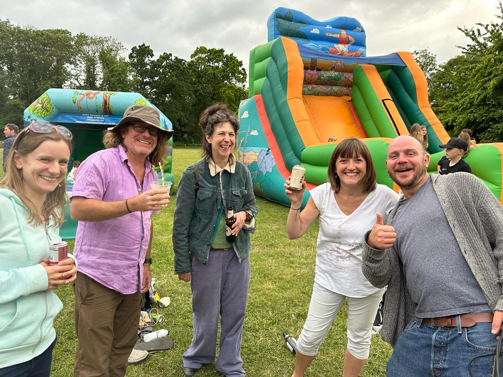 Four people smiling in front of a bouncy castle