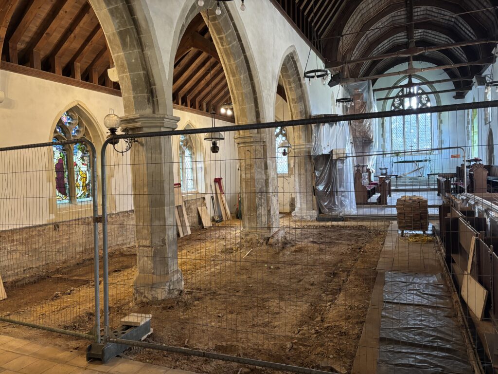 A church undergoing restoration work to its floor with safery fencing in front.