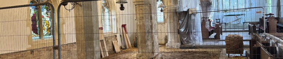 A church undergoing restoration work to its floor with safery fencing in front.