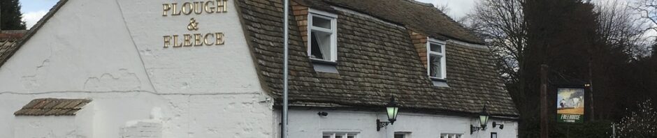 The Plough and Fleece - an old village pub painted white next to the street.