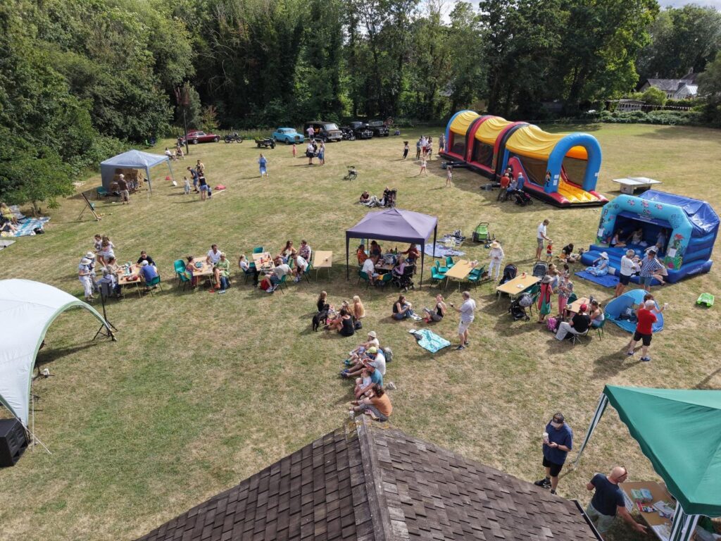 An overhead drone shot of a field with bounch castles and people sat enjoying the sunshine