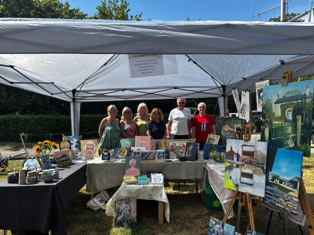 a group of artists under a gazebo showing their artworks.